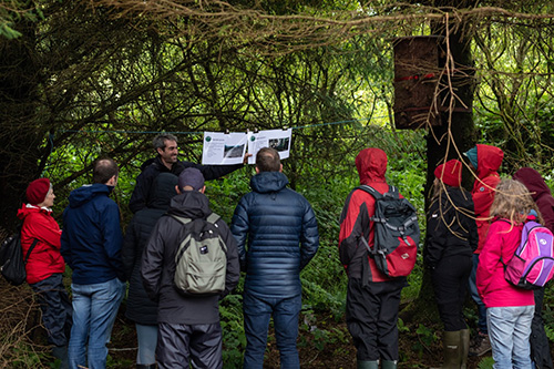 a group of people looking at a paper in a forest